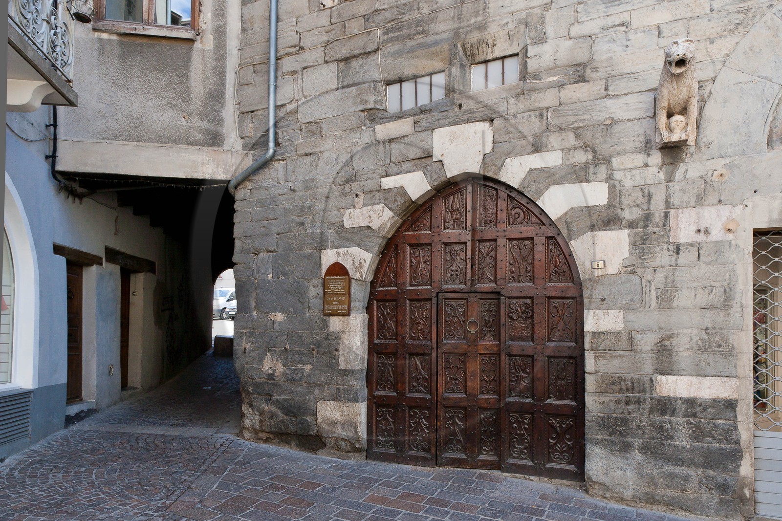 Embrun, Maison des Gouverneurs, Porte Renaissance accostée d'un lion à mi-corps tenant dans ses pattes une tête humaine Embrun, Maison des Gouverneurs, Porte Renaissance accostée d'un lion à mi-corps tenant dans ses pattes une tête humaine